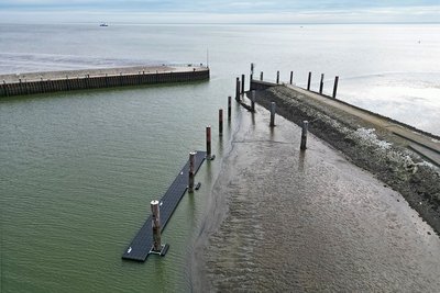 Steg im Hafen Hooksiel von Land aus gesehen mit der Nordsee im Hintergrund