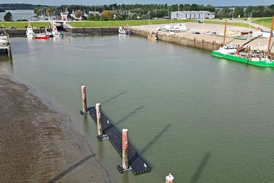Steg im Hafen Hooksiel vom Meer aus gesehen mit dem hafen und Booten im Hintergrund