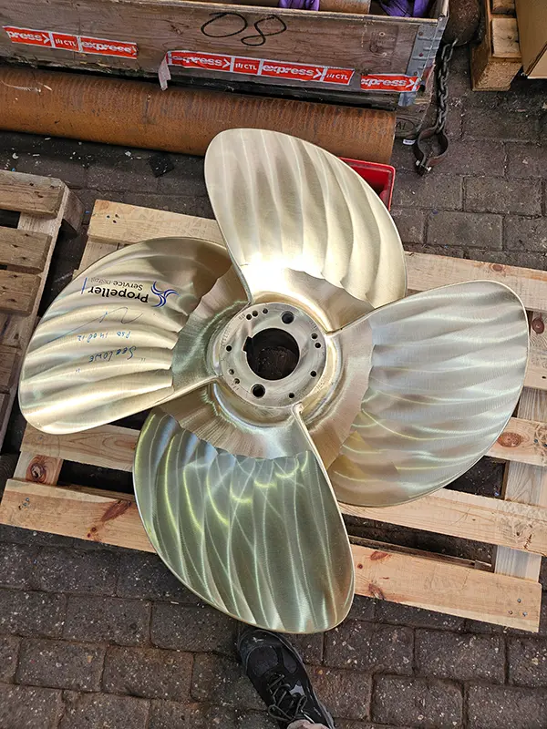 Neuer, hochglanzpolierter Vierblatt-Propeller auf einer Palette, mit Aufkleber des Propellerherstellers und Beschriftung „Seelöwe“.