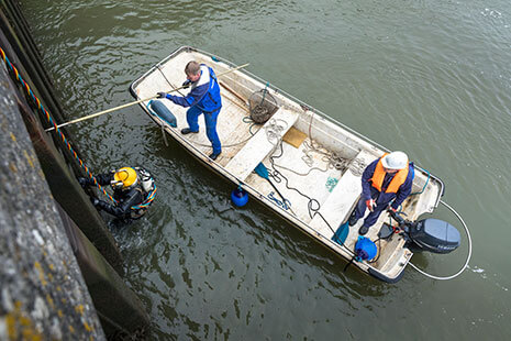 Taucher an der Kaikante mit Team im Boot