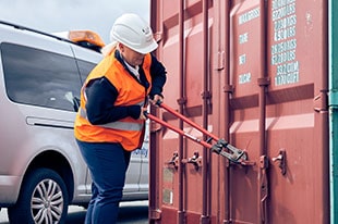 Eine Mitarbeiterin des Port Office öffnet einen Schiffscontainer
