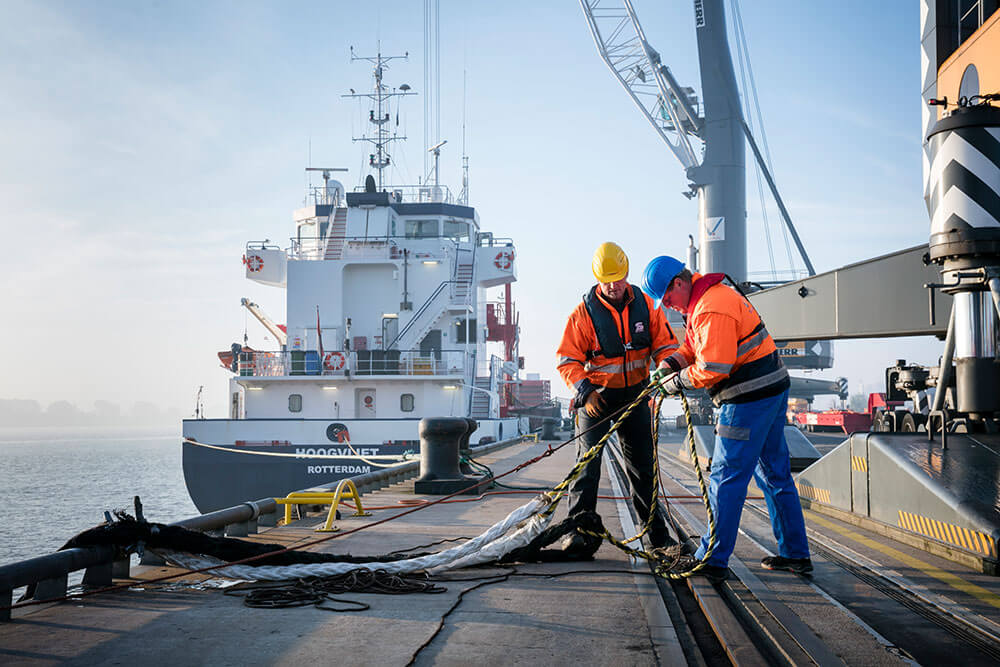Festmacher im Hafen bei der Arbeit Zwei Festmacher arbeiten an dicken Seilen