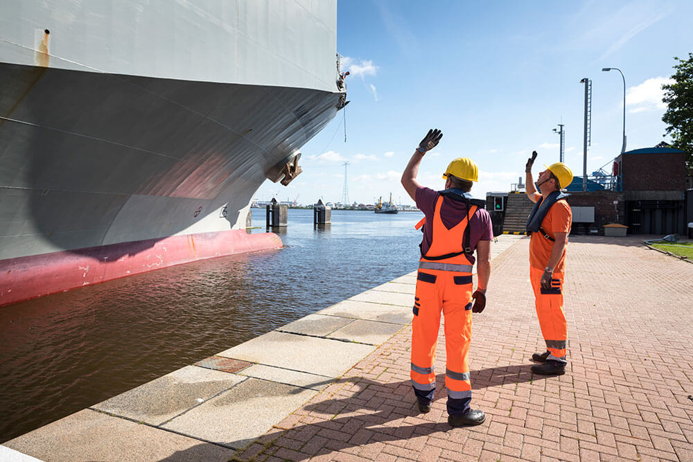 Festmacher im Hafen bei der Arbeit Zwei Festmacher winken hoch zu einem Schiff in der Schleuse