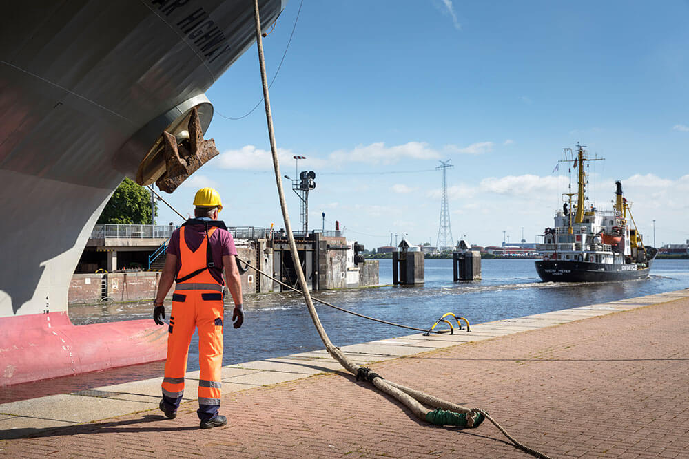 Festmacher im Hafen bei der Arbeit Ein Festmacher beobachtet die Ausfahrt eines Schiffes aus der Schleuse