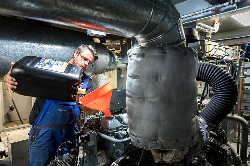 ein Matrose füllt Öl auf einen Motor auf
