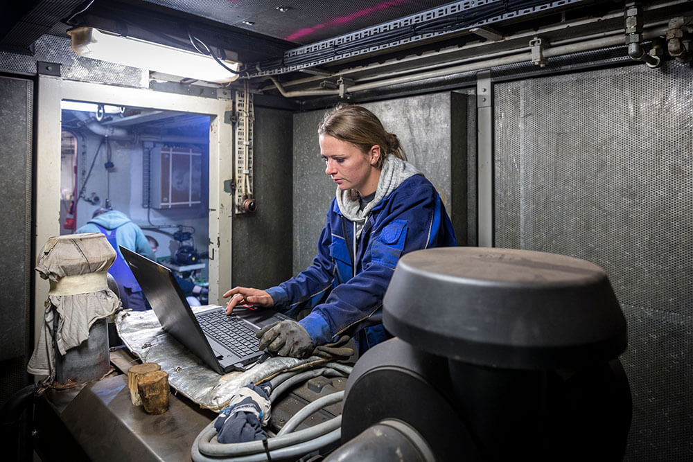 eine Matrosin unter Deck konzentriert an einem Laptop