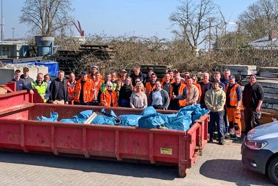 Cleanup-Team hinter einem Container voller Müllsäcke