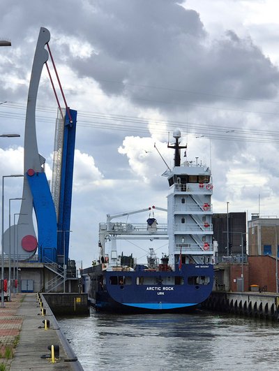 Frachtschiff „Arctic Rock" bei der Schleusung in der Nesserlander Schleuse in Emden, daneben die hochgeklappte blau-graue Klappbrücke.