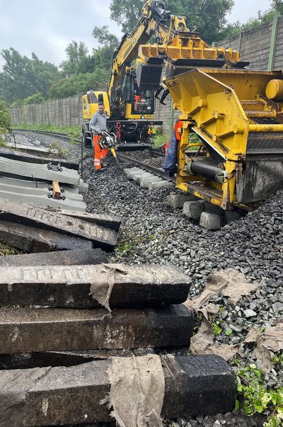 Zweiwegebagger: Mit einem Zweiwegebagger und einer Schotterreinigungsmaschine (SRM) sind alte Schwellen entfernt, alter Schotter aufgenommen und in die SRM gefüllt, neue Schwellen gesetzt, gereinigter Schotter eingebaut und die Schotteroberfläche geglättet worden