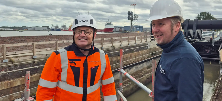 NPorts-Projektleiter Wilfried Schleusener (links, orange Warnjacke) und Niederlassungsleiter Aiko Hollander (rechts) auf einem Gerüst an der Großen Seeschleuse Emden, dahinter Hafen und Schiffe.