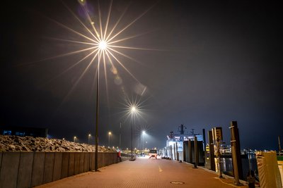 Reihe von leuchtenden Straßenlaternen im dunkeln an der Kaikante
