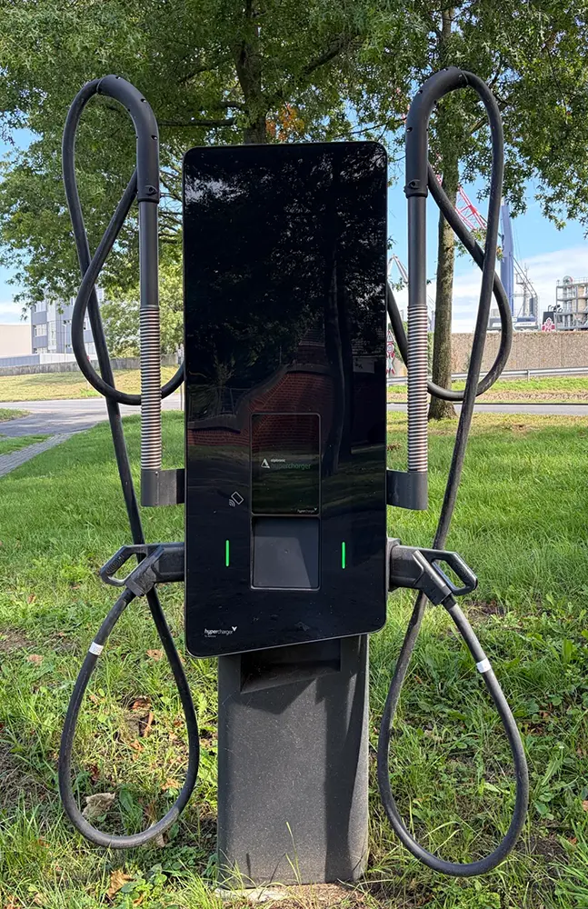 Eine Schnellladesäule für Elektroautos mit zwei fest angeschlossenen Ladekabeln auf einer Grünfläche im Hafen Brake.