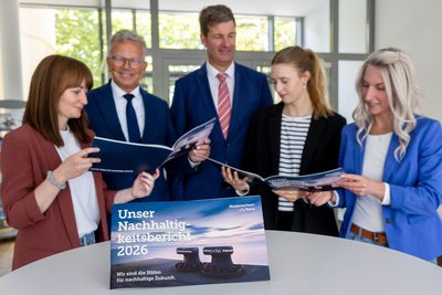 Blättern gemeinsam im neuen Nachhaltigkeitsbericht von Niedersachsen Ports: die Projektverantwortlichen (vorne, von links) Katja Mädler, Denise Schablitzki und Jantje Ziegeler mit den Geschäftsführern Holger Banik und Volker Weiß. (Foto: Burmann/NPorts)