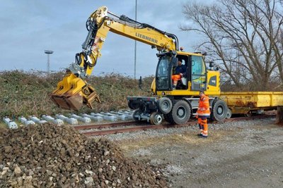 Zweiwegebagger auf Gleisen mit zwei Arbeitern