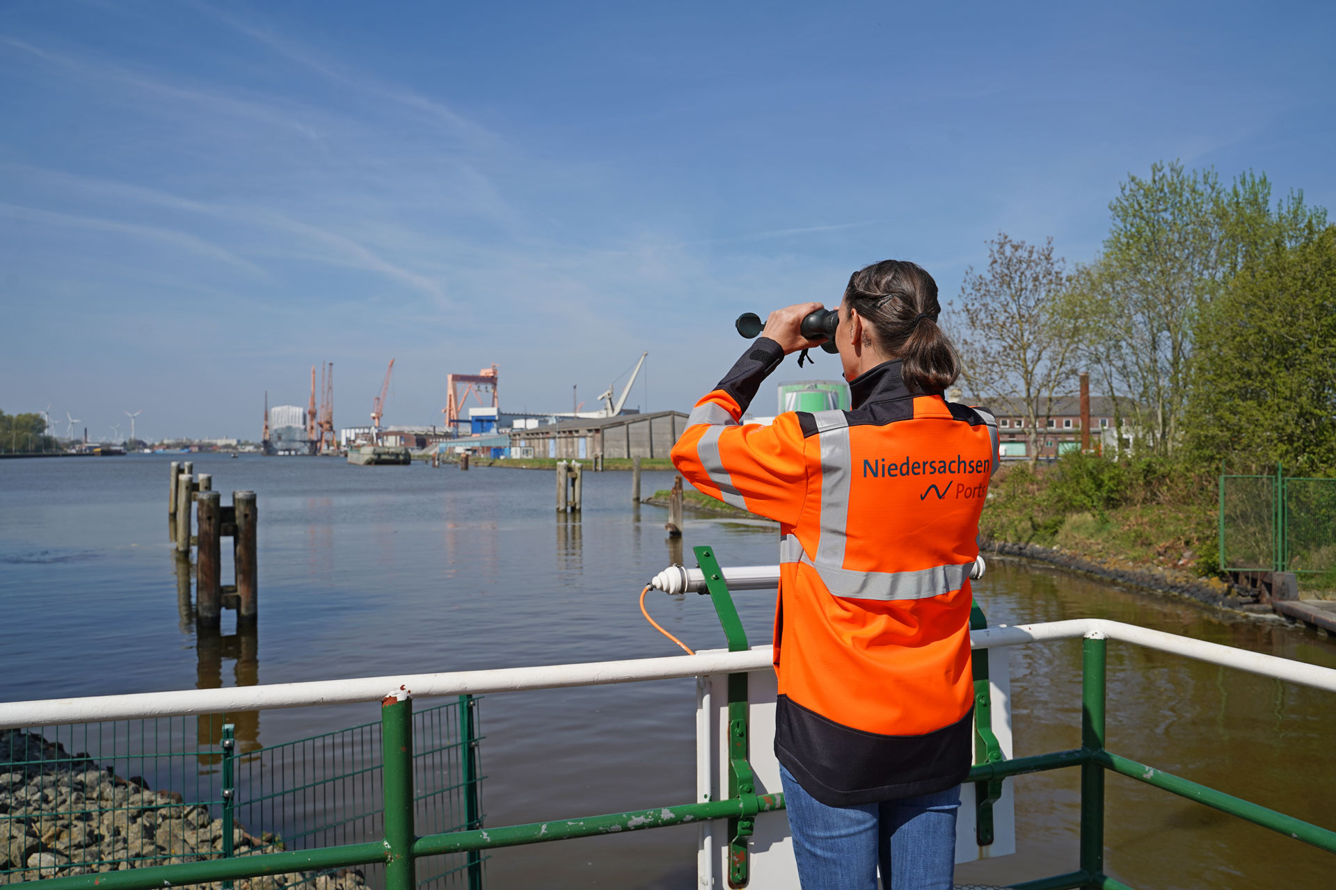 Tomke Steenblock blickt mit dem Fernglas von der Schleuse nach Schiffen aufs Wasser