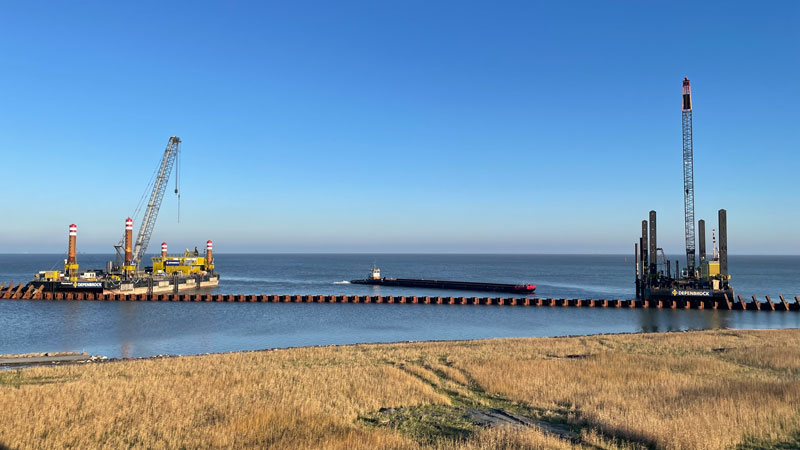 Blick zur Baustelle Liegeplatz 5-7 in Cuxhaven: links rüttelt „Simone“ die Tragrohre in den Baugrund, in der Mitte bringt der Schlepper gerade eine Arbeitsschute mit den Pfählen, die später rechts von der Schrägpfahlramme „Annegret“ in den Boden eingerammt werden. 