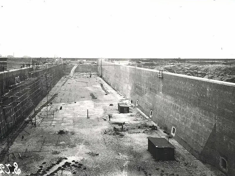 Historisch: Schleusenkammer im Bau Historische Schwarz-Weiß-Aufnahme der leeren Schleusenkammer der Großen Seeschleuse Emden während der Bauzeit, links ein Baugerüst an der Kammerwand.