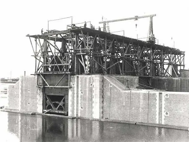 Historisch: Bau des Torhauses Historische Schwarz-Weiß-Aufnahme vom Bau der Großen Seeschleuse Emden. Ein hohes Holzgerüst mit Kran steht über dem gemauerten Torbereich.