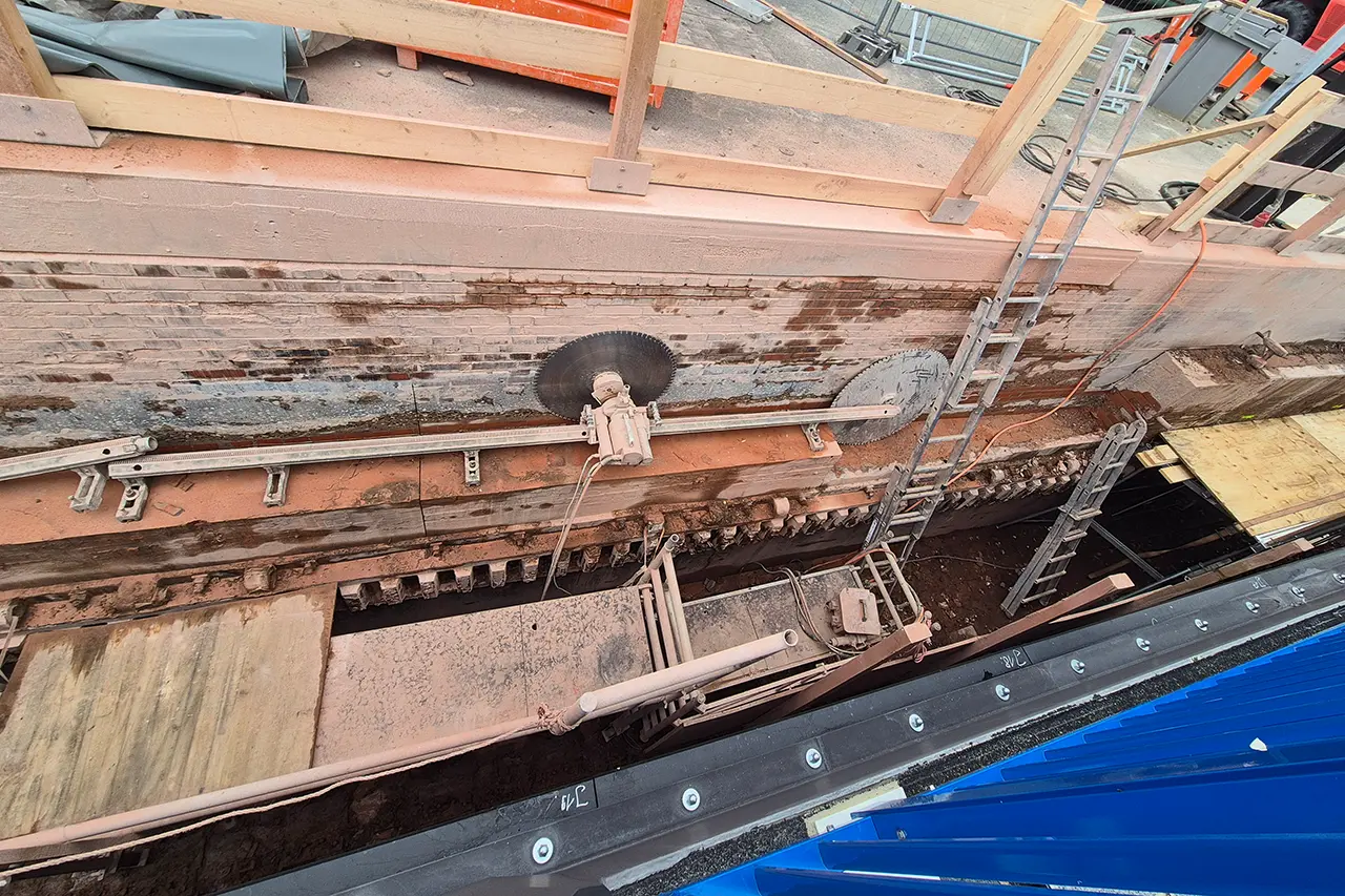 Sägearbeiten am Mauerwerk Blick von oben in die Baugrube: Eine Wandsäge mit zwei Sägeblättern schneidet auf einer Führungsschiene durch das alte Mauerwerk der Schleuse.