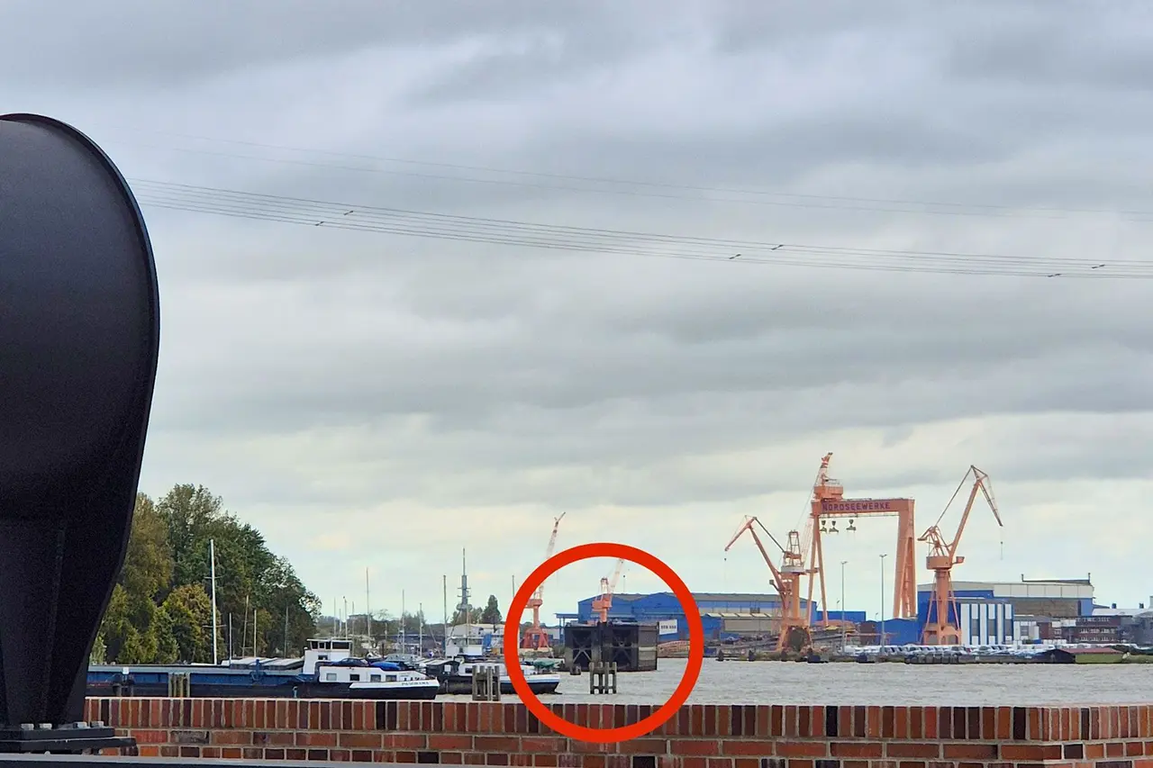 Hafenpanorama mit Markierung Blick über das Hafenbecken in Emden auf die Kräne der Nordseewerke. Ein roter Kreis markiert ein Bauteil der Großen Seeschleuse im Wasser.